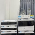 Peralatan High Performance Liquid Chromatography (HPLC) Agilent yang terdiri dari unit pemroses data di sebelah kiri dan autosampler dengan botol-botol sampel kaca di sebelah kanan, menunjukkan sistem analitik modern untuk pemisahan dan identifikasi sampel kimia